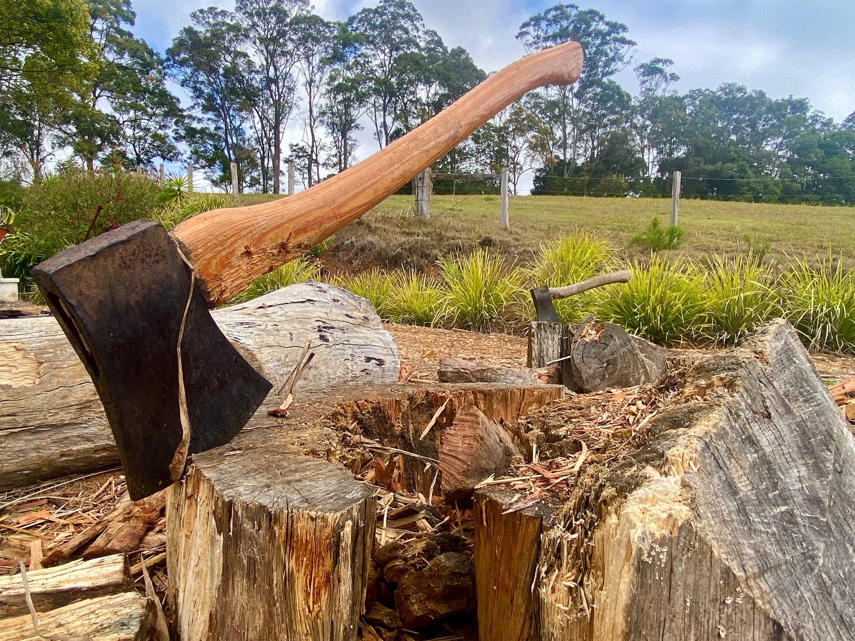 An axe is sitting on top of a piece of wood.